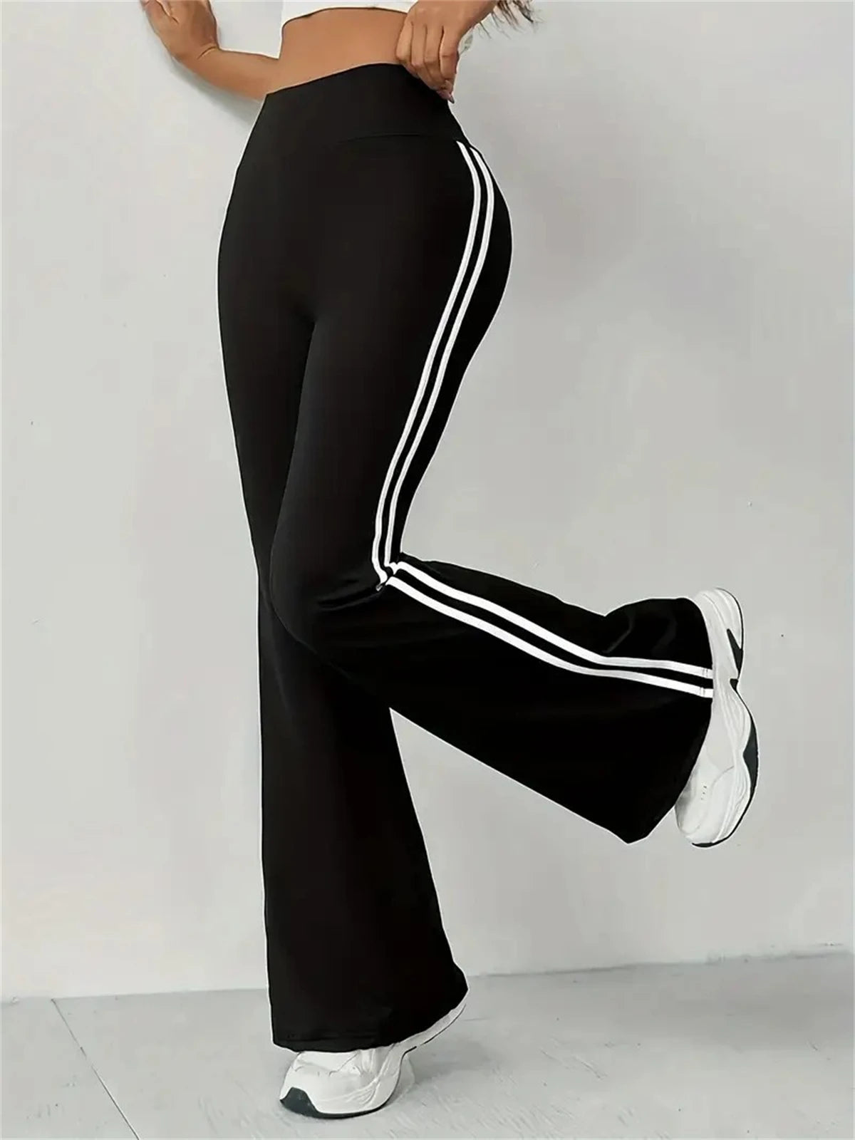Pantalon évasé noir taille haute avec bandes blanches sur le côté et bas évasé.