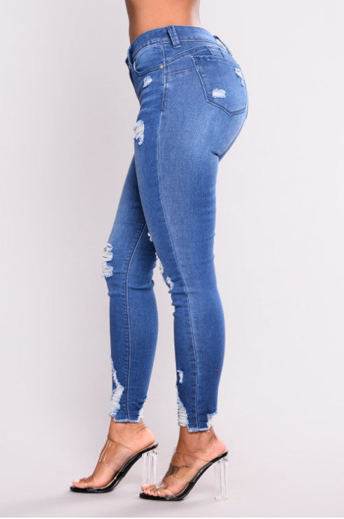 Jean slim bleu taille haute, vue de côté, jambes fuselées et déchirures aux genoux