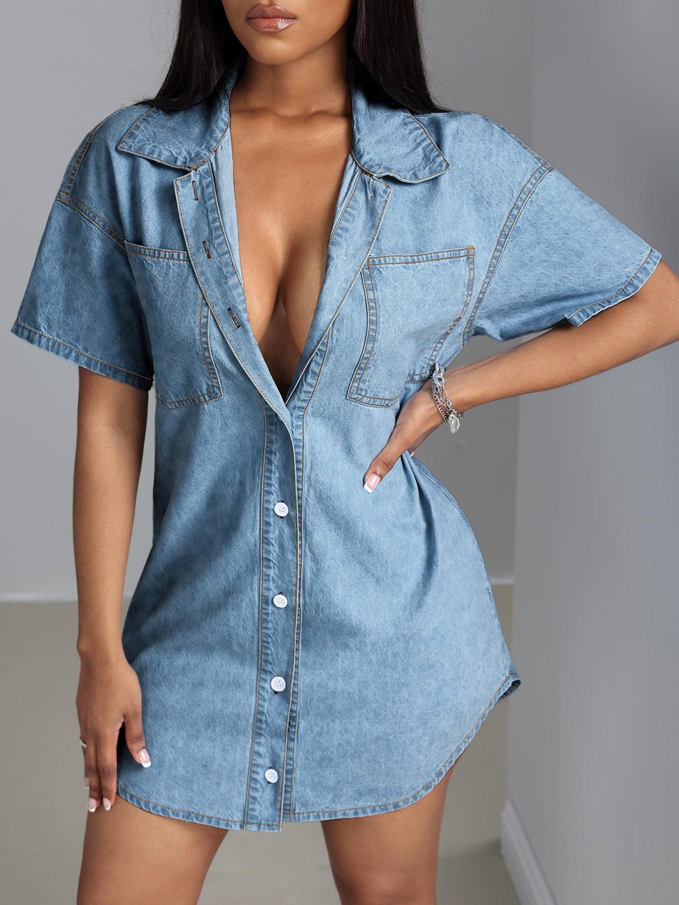 Robe chemise en jean bleu, col claudine et poche poitrine, manches courtes, boutons visibles.