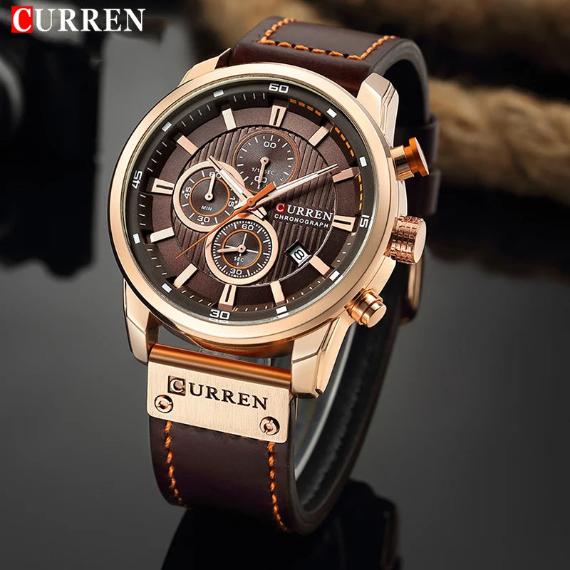 Montre-bracelet CURREN cadran noir quadrillé, boîtier doré rosé, bracelet cuir foncé.