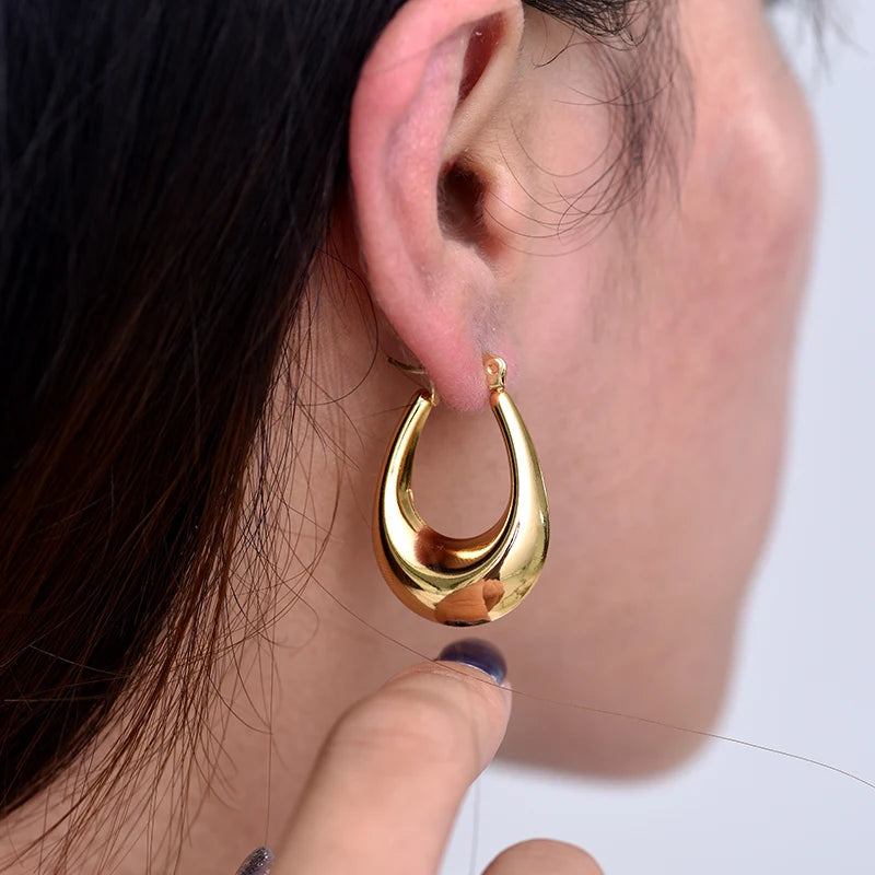 Boucles d’oreilles créoles épaisses dorées, vue de profil sur l’oreille.