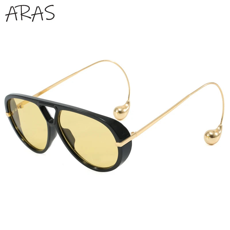 Lunettes de soleil ovales surdimensionnées vue de côté, monture noire et verres jaunes