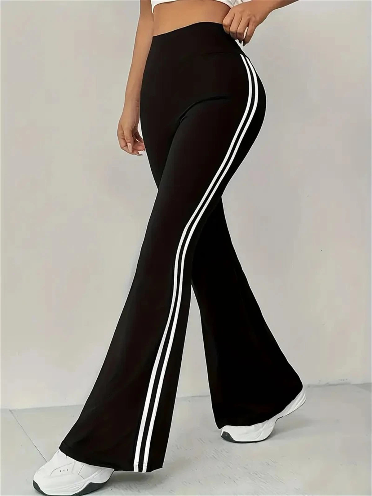 Pantalon évasé taille haute noir, bandes blanches latérales et bas évasé.