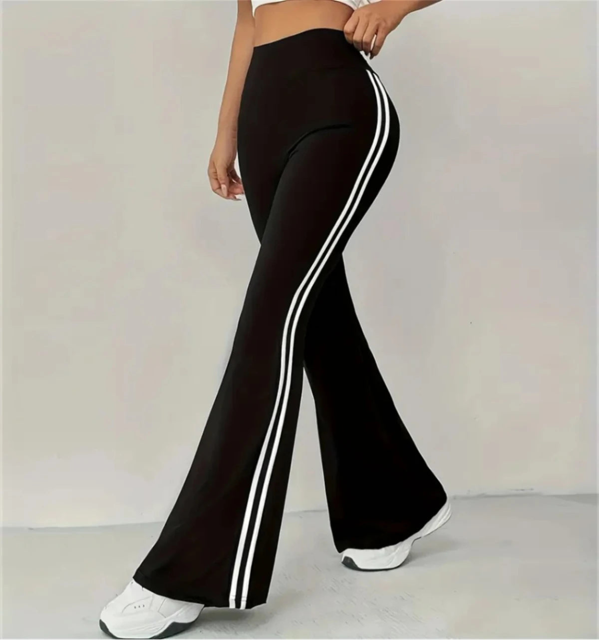 Pantalon évasé taille haute noir, bandes contrastées blanches sur le côté.