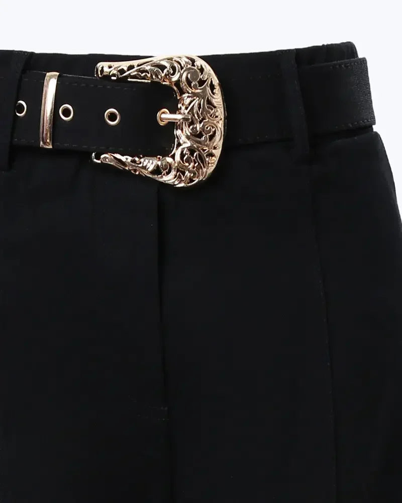 Ceinture du pantalon noir : grande boucle dorée décorative, passants et œillets