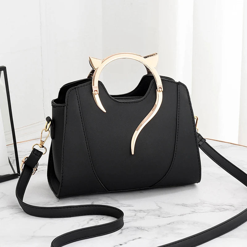 Mini sac à main noir avec poignée chat dorée et bandoulière, forme à rabat