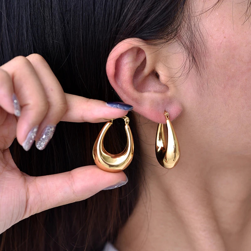 Boucles d’oreilles créoles épaisses dorées portées, vue de l’oreille et du fermoir.