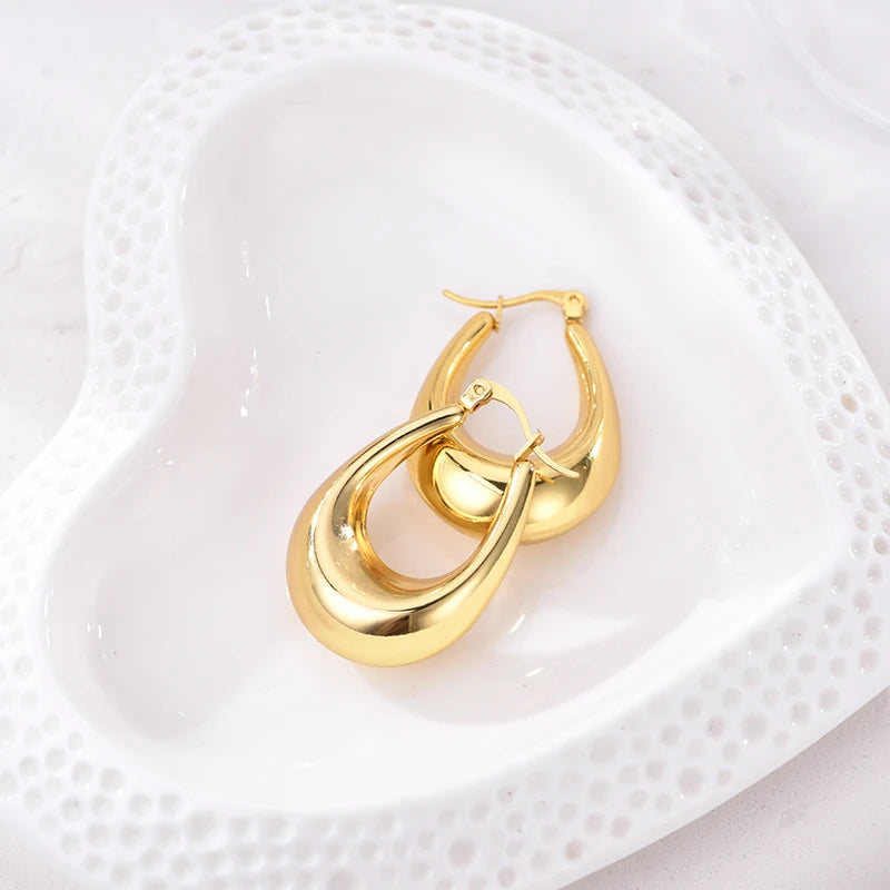 Boucles d’oreilles créoles épaisses dorées, finition brillante, présentées sur support.