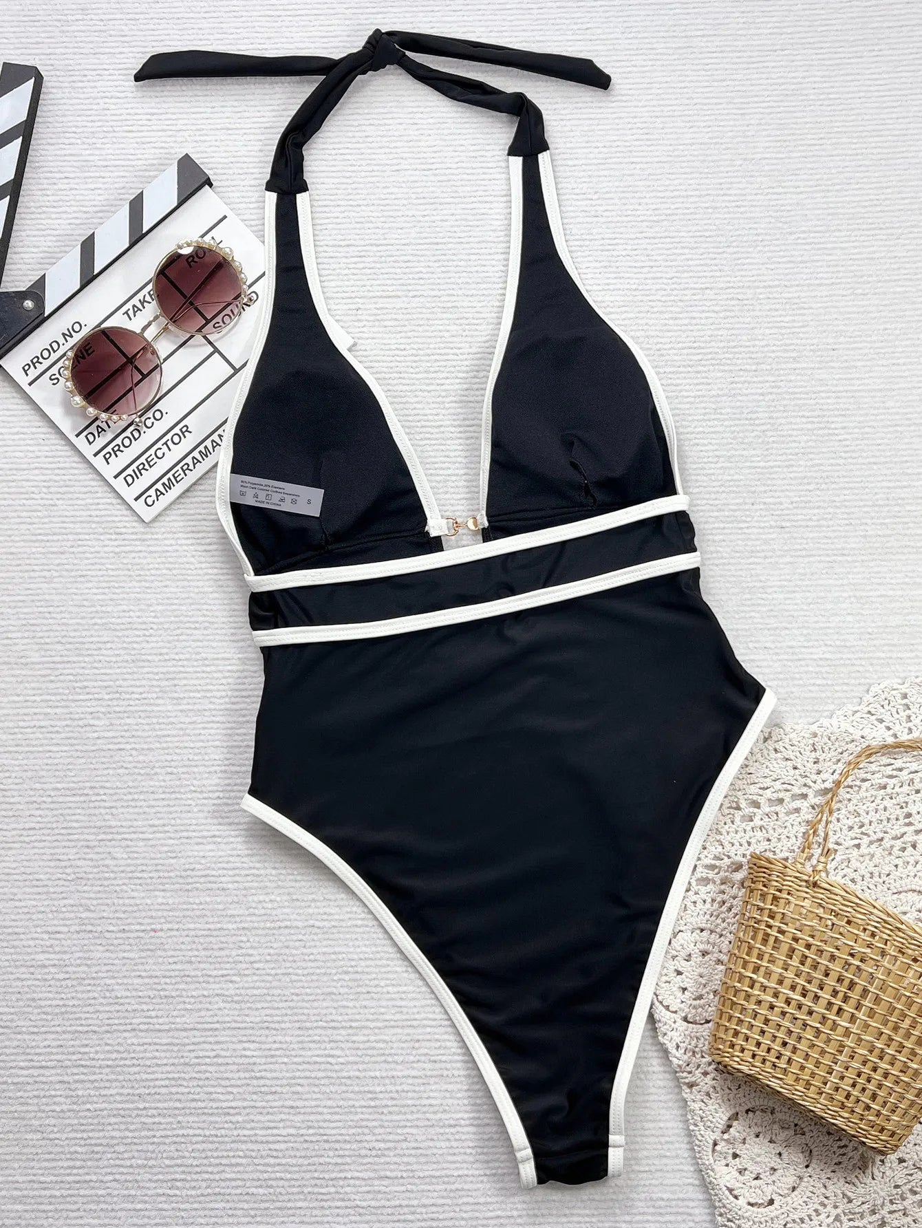 Maillot de bain une pièce noir avec liserés blancs, col en V, fermeture au milieu du buste.