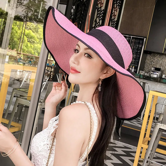 Chapeau de paille femme pliable rose, bord noir et visière ample pour la plage.