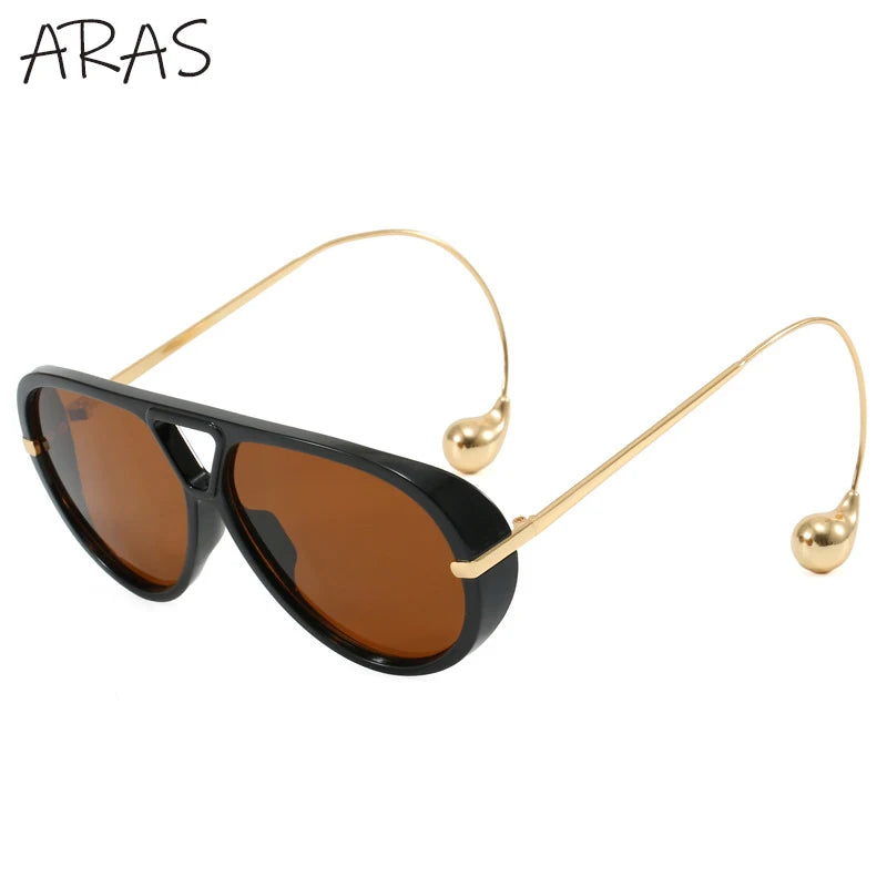 Lunettes de soleil ovales noires à verres bruns, monture métal doré, branches avec billes