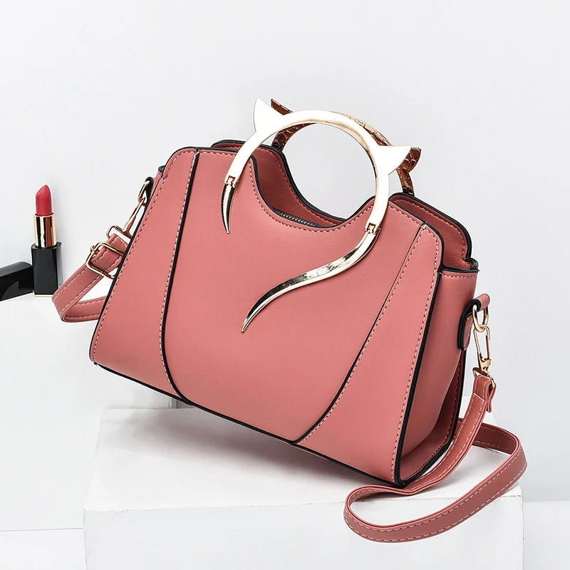 Mini sac à main rose avec poignée chat, bandoulière, détail métal doré.