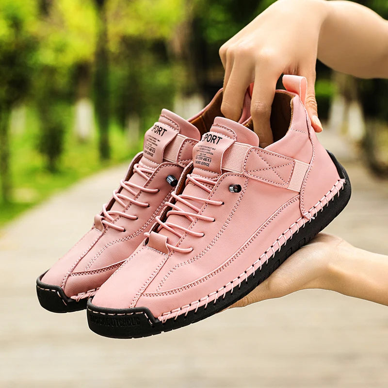 Mocassins femme en cuir roses à lacets, paire tenue par une main, semelle noire.