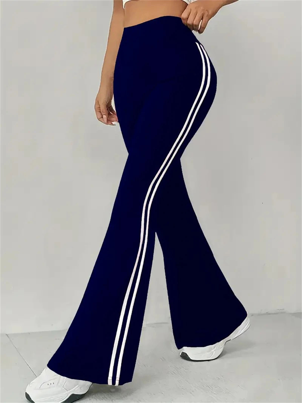Pantalon évasé taille haute bleu foncé, bandes blanches contrastées sur le côté.