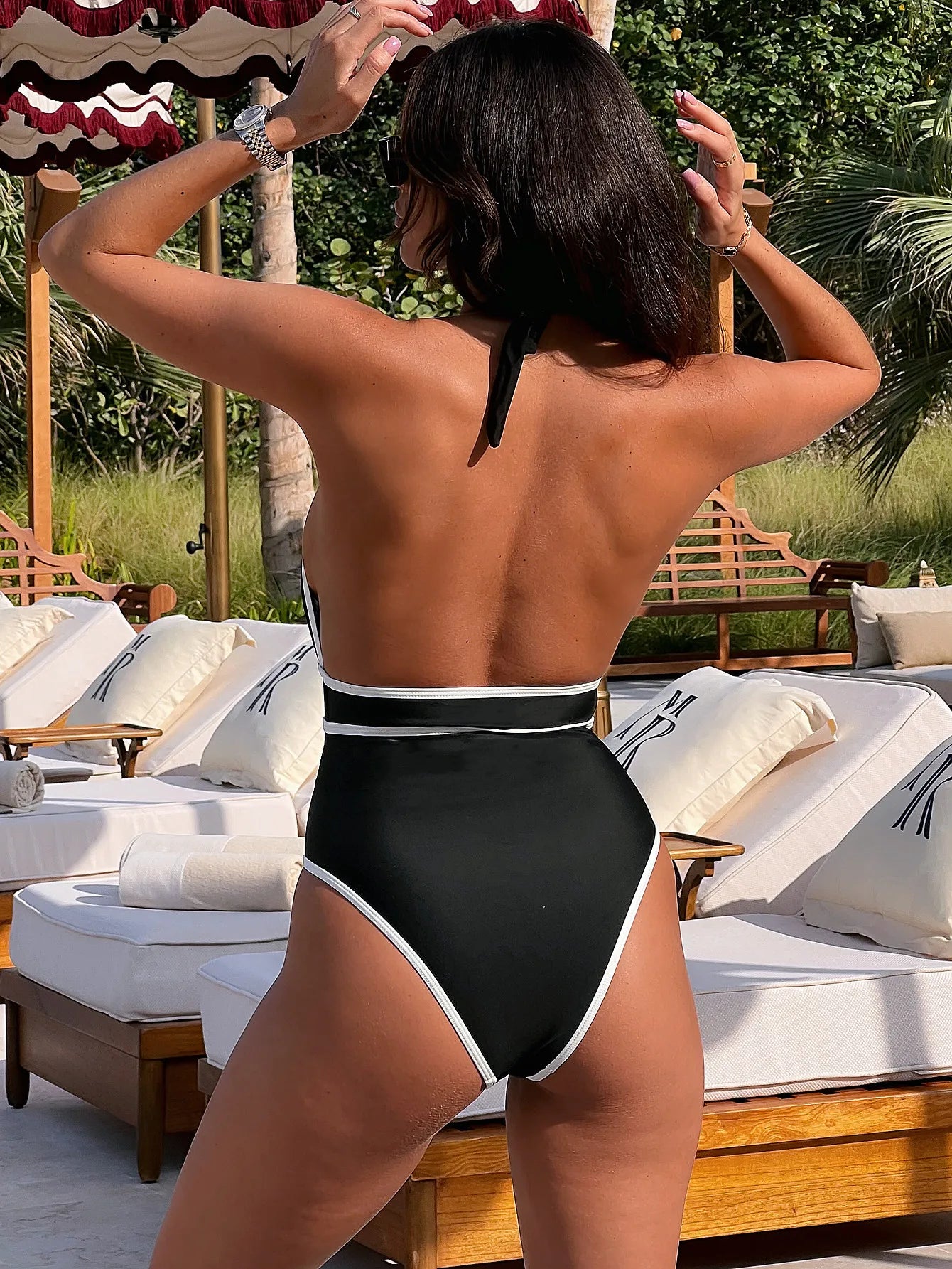 Maillot de bain une pièce noir à dos nu avec bandes blanches et détails de fermeture.