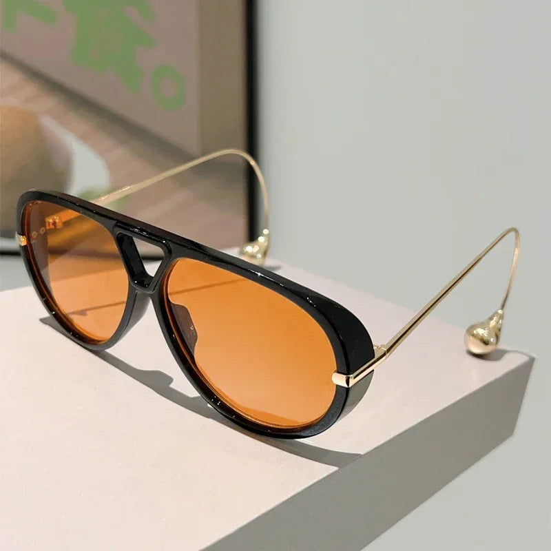 Lunettes de soleil pilote surdimensionnées à monture noire, verres orange teintés.